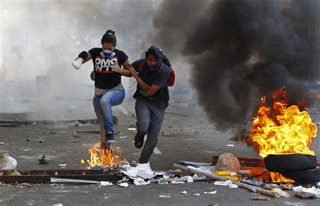 Demonstrators run for cover as they confront police during a protest against the government of President Nicolas Maduro in Caracas, February 22, 2014. REUTERS/Carlos Garcia Rawlins