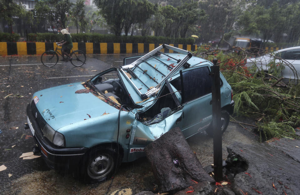 A car stands damaged after a tree fell on it in Mumbai, India, Monday, May 17, 2021. Cyclone Tauktae, roaring in the Arabian Sea was moving toward India's western coast on Monday as authorities tried to evacuate hundreds of thousands of people and suspended COVID-19 vaccinations in one state. (AP Photo/Rafiq Maqbool)