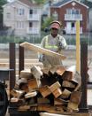 In this Wednesday, Aug. 15, 2012 photo, Andre Scott, of Jersey City, N.J., throws a piece of trimmed wood cut from discarded tree trunk at Citilog in Newark, N.J. The Newark company takes unwanted trees from the so-called urban forest — parks, yards, streets and wherever else a tree might grow in a city — and turns them into furniture, flooring and other materials. (AP Photo/Mel Evans)