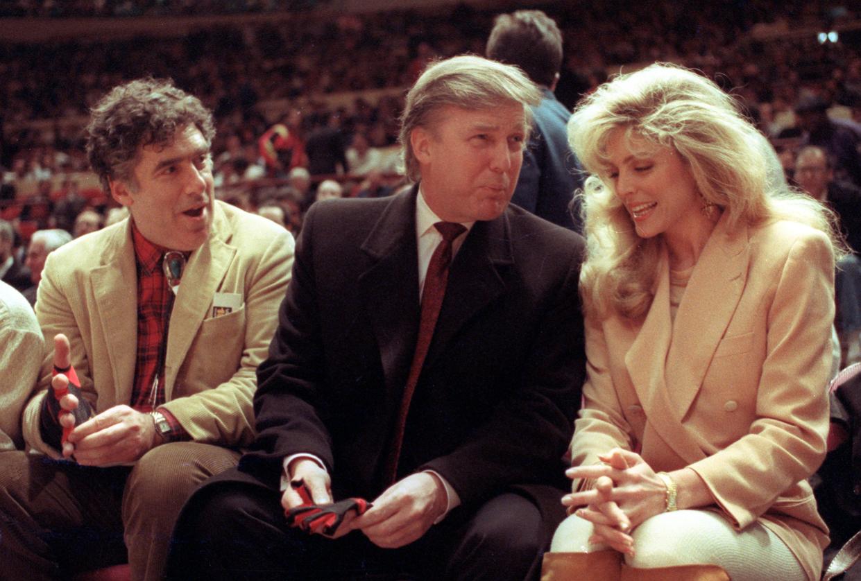 Actor Elliott Gould, left, joins Donald Trump and Marla Maples at courtside during the New York Knicks game against the Phoenix Suns at New York's Madison Square Garden on March 6, 1991.