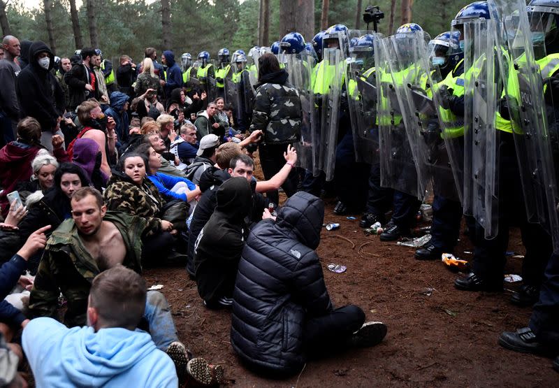 Revellers sit after a police shut down a suspected illegal rave, in Thetford Forest