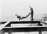 <p>Silent-era comedian, Harold Lloyd (star of <em>Safety Last</em><em>!</em>), poses as a wheelbarrow on the edge of a construction beam.</p>