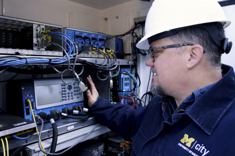 This undated photo provided by the University of Michigan College of Engineering shows Jim Lollar, Mcity test facility manager, as he works inside of a traffic control cabinet at the Mcity Test Facility, identical to ones found at signalized intersections across the country. Smarter vehicles could mean some of the most dramatic changes for the traditional traffic signal since the yellow light was added more than a century ago. (Jeremy Little/University of Michigan College of Engineering via AP)