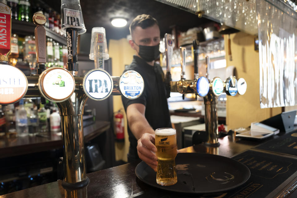 A member of staff serves a drink, as pubs, cafes and restaurants in England reopen indoors under the latest easing of the coronavirus lockdown, in Manchester, England, Monday, May 17, 2021. Pubs and restaurants across much of the U.K. are opening for indoor service for the first time since early January even as the prime minister urged people to be cautious amid the spread of a more contagious COVID-19 variant. (AP Photo Jon Super)