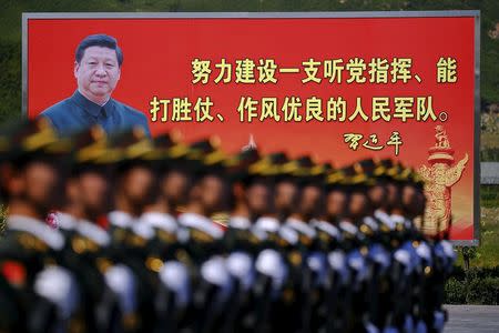 A picture of Chinese President Xi Jinping is seen on a billboard behind soldiers of China's People's Liberation Army marching during a training session for a military parade to mark the 70th anniversary of the end of World War Two, at a military base in Beijing, China, August 22, 2015. REUTERS/Damir Sagolj