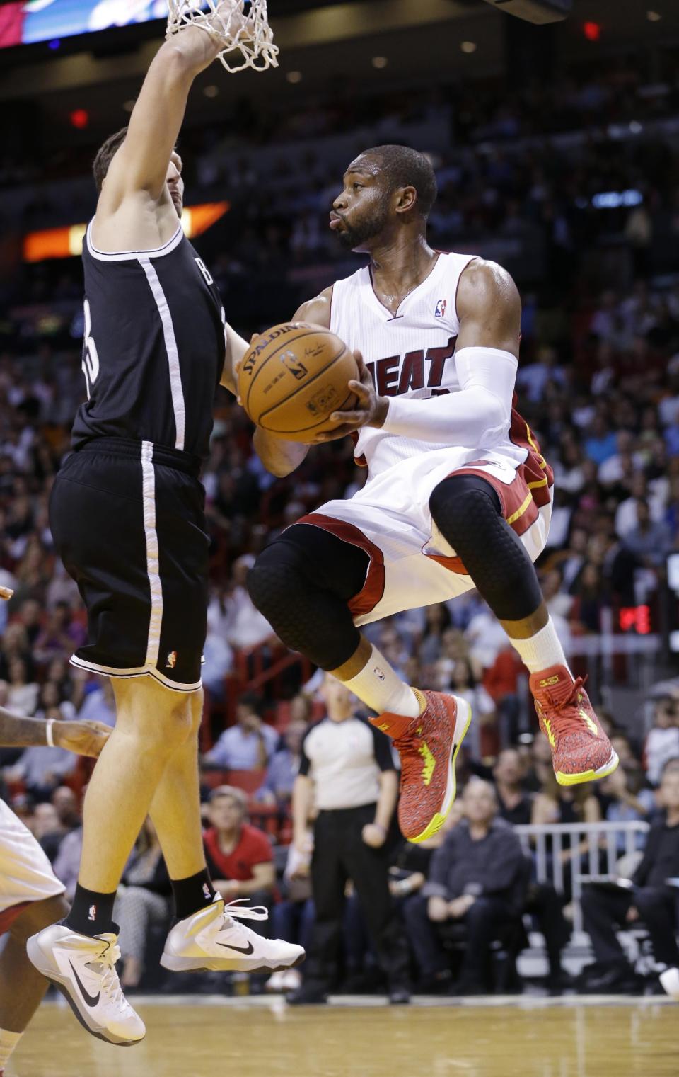Miami Heat guard Dwyane Wade, center, looks for an open teammate as he is guarded by Brooklyn Nets forward Mirza Teletovic, of Bosnia, during the first half of an NBA basketball game, Wednesday, March 12, 2014, in Miami. (AP Photo/Wilfredo Lee)