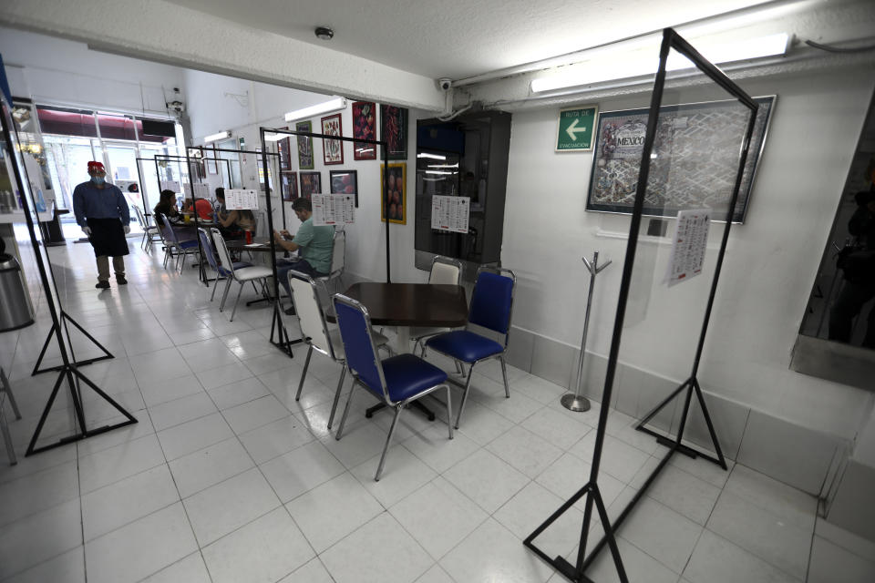 Separated by transparent dividers, customers eat in a restaurant while keeping their distance to help curb the spread of the new coronavirus, in Mexico City, Wednesday, July 1, 2020. (AP Photo/Eduardo Verdugo)