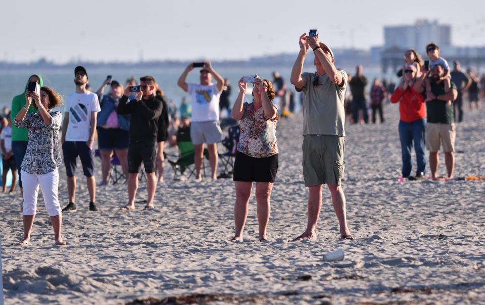 People on the beach in Cape Canaveral watch Sunday's launch of a Falcon 9 rocket on the Starlink 6-39 mission from Launch Complex 40 at Cape Canaveral Space Force Station.