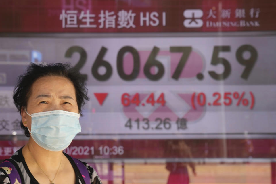 A woman wearing a face mask walks past a bank's electronic board showing the Hong Kong share index in Hong Kong, Tuesday, Oct. 26, 2021. Asian shares were mostly higher Tuesday after another rally to a record high on Wall Street. (AP Photo/Kin Cheung)