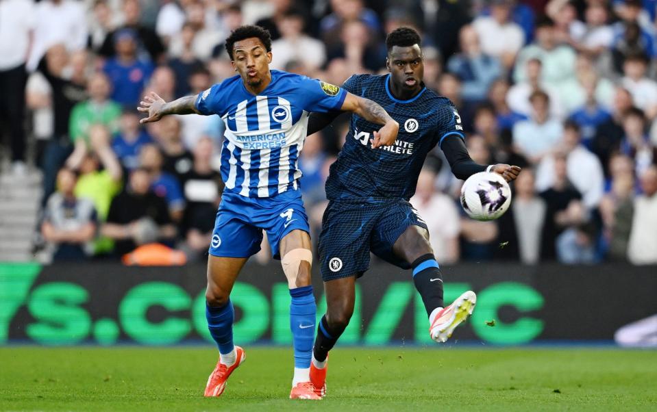 Benoit Badiashile of Chelsea passes the ball whilst under pressure from Joao Pedro of Brighton & Hove Albion during the Premier League match between Brighton & Hove Albion and Chelsea FC at American Express Community Stadium on May 15, 2024 in Brighton, England