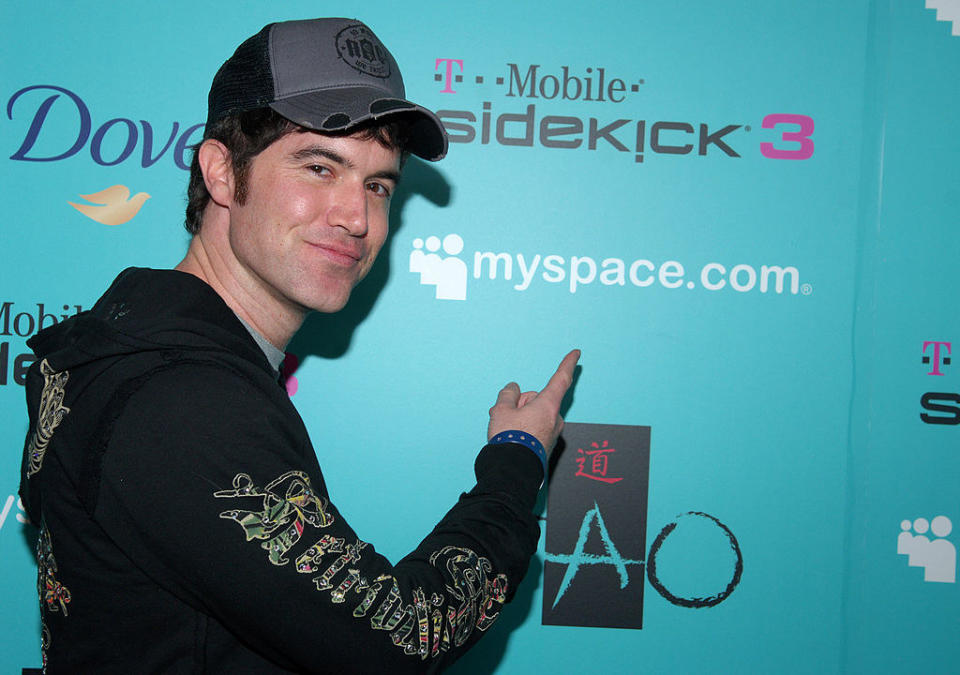 Tom Anderson pointing at a Myspace dot com sign