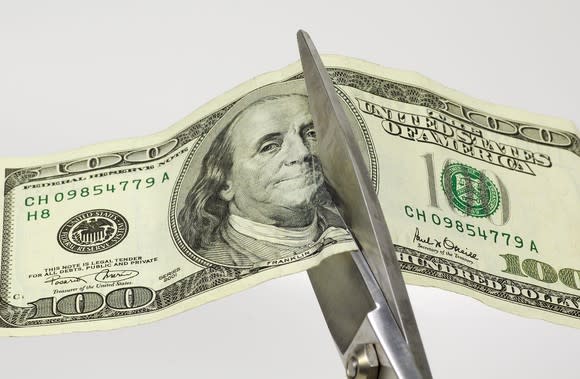 Scissors cutting a hundred dollar bill in half.