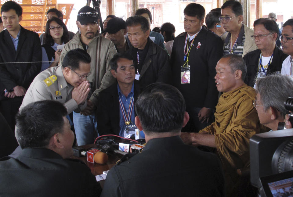 In this photo taken Monday, Jan. 27, 2014, local monk protest leader Luang Pu Buddha Issara, right, is greeted high level police officers asking him to leave the neighboring government building to Bangkok, Thailand. Some government officials have resorted to pleading with protests occupying their government offices where daily functions such as passport controls and immigration issues are backing up. It was an extraordinarily humbling moment for Prime Minister Yingluck Shinawatra's embattled administration, which ascended to power following a landslide election two and a half years ago. (AP Photo/Thanyarat Doksone)