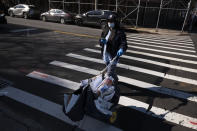 In this Thursday, March 26, 2020 photo, a postal worker wears a mask and gloves as she delivers the mail in the Brooklyn borough of New York. Is it safe to open your mail? How about that cardboard package of groceries you ordered online? Health experts say the biggest risks remains when you encounter someone with the coronavirus and washing your hands and avoiding touching your face are the best ways to stay safe. (AP Photo/Mark Lennihan)