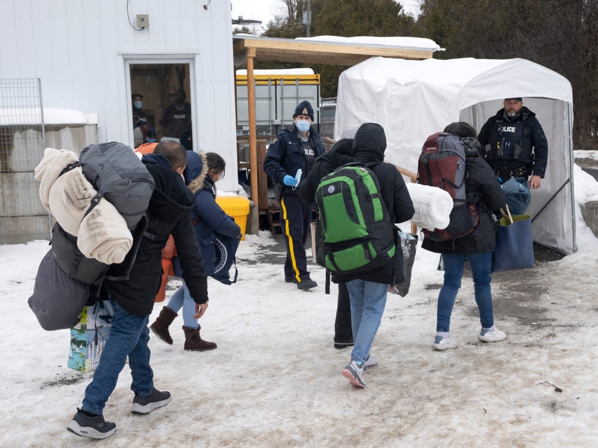A family of asylum seekers from Colombia is met by RCMP officers after crossing the border at Roxham Road into Canada on February 9, 2023. Sources tell Radio-Canada the Canadian and American governments have reached a deal which would shut down the irregular border crossing. (Ryan Remiorz/The Canadian Press - image credit)