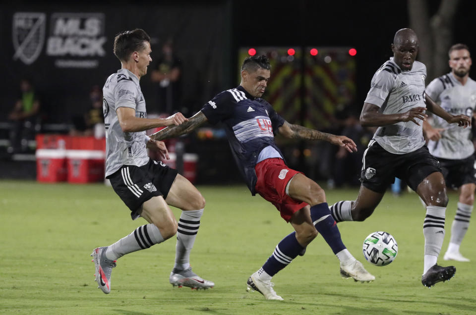 New England Revolution forward Gustavo Bou, center, attempts a shot against Montreal Impact defender Jukka Raitala, left, and defender Rod Fanni, right, during the first half of an MLS soccer match, Thursday, July 9, 2020, in Kissimmee, Fla. (AP Photo/John Raoux)