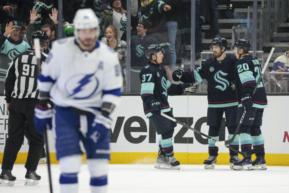 Seattle Kraken right wing Oliver Bjorkstrand, second from right, celebrates his goal with center Yanni Gourde (37) and right wing Eeli Tolvanen (20) as Tampa Bay Lightning right wing Nikita Kucherov (86) skates away during the second period of an NHL hockey game Saturday, Dec. 9, 2023, in Seattle. (AP Photo/Jason Redmond)