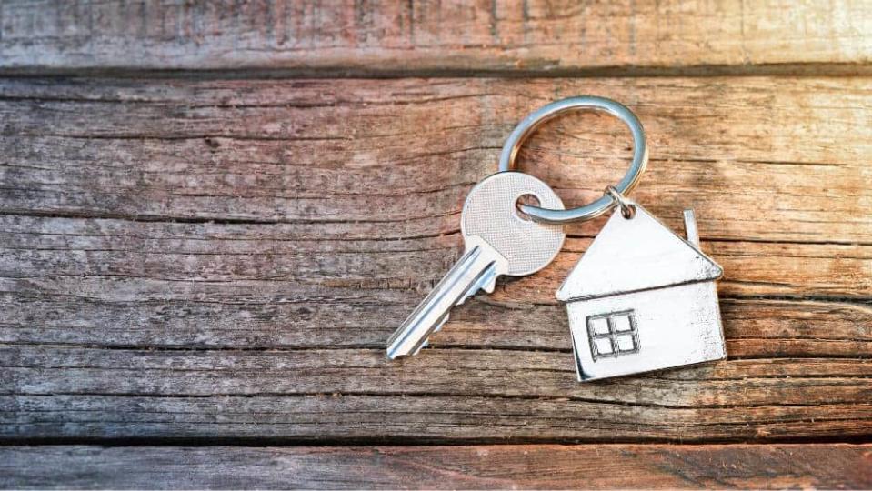 House Key And Keychain On Wooden Table