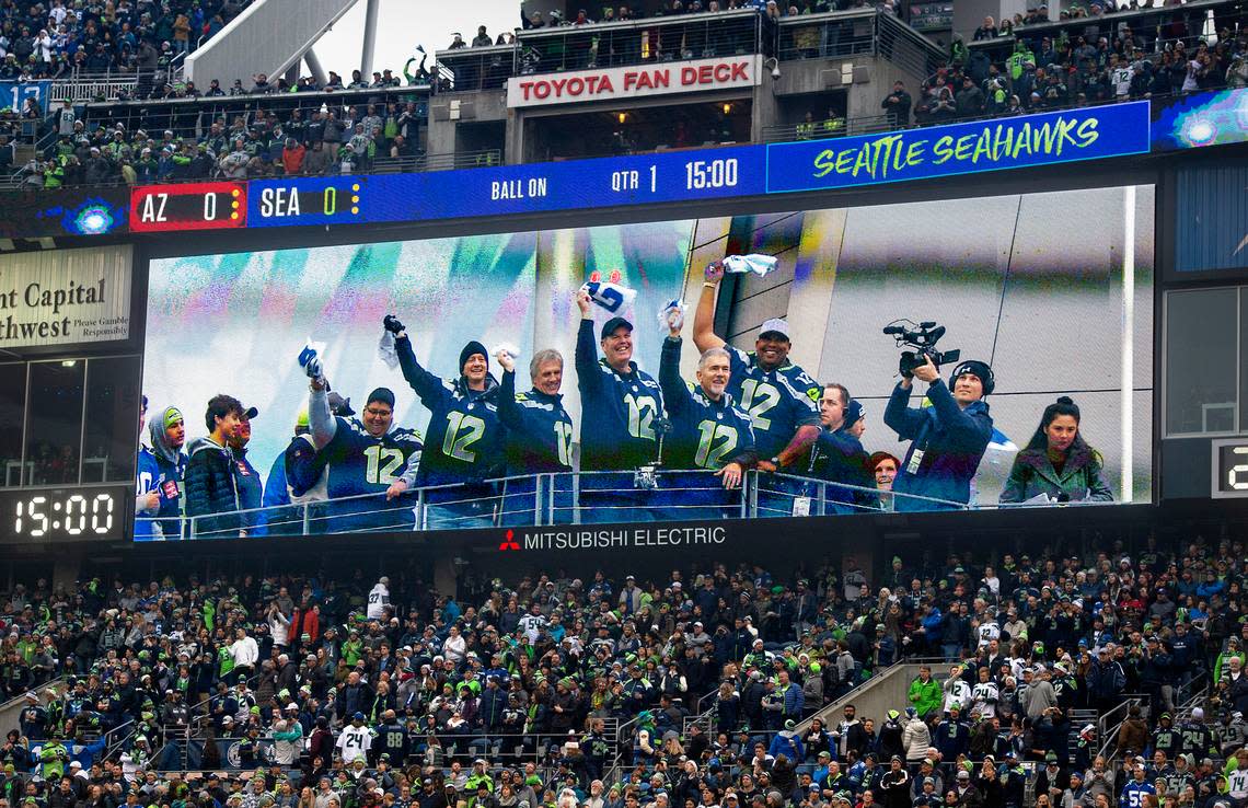 Tumwater High football coach Bill Beattie (center) raises the 12th Man flag before the Seattle Seahawks NFL football game against the Arizona Cardinals at Centurylink Field on Sunday, Dec. 22, 2019. Beattie was awarded the Washington State High School Football Coach of the Year earlier in the day.