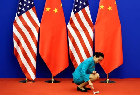 FILE PHOTO: An attendent cleans the carpet next to U.S. and Chinese national flags in Beijing
