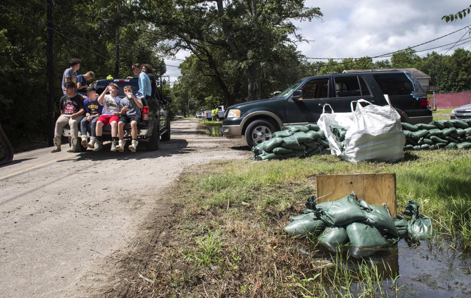 Fisher High School students rest in the back of a truck after they helped place sandbags around the Lafitte, La., area as residents prepare for the arrival of two tropical storms along the south Louisiana coast on Monday, Aug. 24, 2020 . (Chris Granger/The Times-Picayune/The New Orleans Advocate via AP)