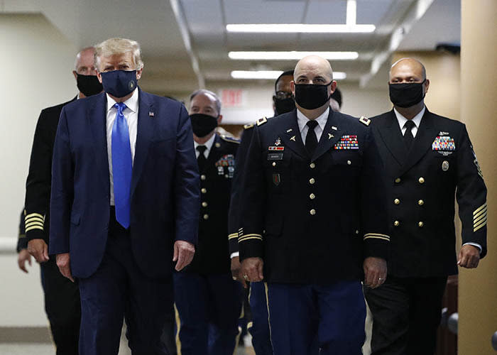 President Donald Trump wears a face mask as he walks down a hallway during a visit to Walter Reed National Military Medical Center in Bethesda, Md.