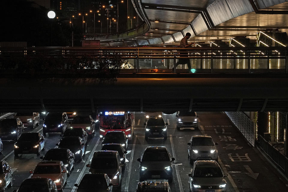 FILE - A man walks across a pedestrian bridge as motorists sit in heavy traffic below in Shanghai, China, Aug. 25, 2021. Global carbon pollution this year has bounced back to almost 2019 levels, after a drop during pandemic lockdowns. A new study by climate scientists at Global Carbon Project finds that the world is on track to put 36.4 billion metric tons of invisible carbon dioxide. (AP Photo/Andy Wong, File)