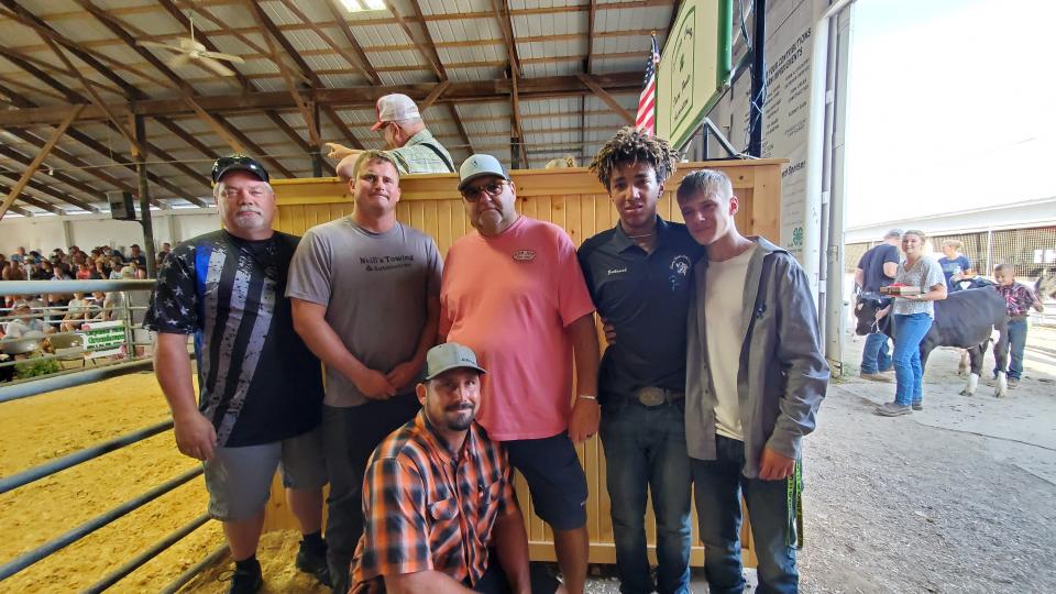 Pictured standing from left are John Birdwell, Jake Neill, Craig Pelham, Zachariah Stephens and Isiah Stephens' best friend Lucas Morse, and, kneeling, Mike Neill, at the 4-H auction at the 2022 Lenawee County Fair where several supporters, including those pictured, contributed several thousand dollars toward a scholarship fund in Isiah Stephens' memory.