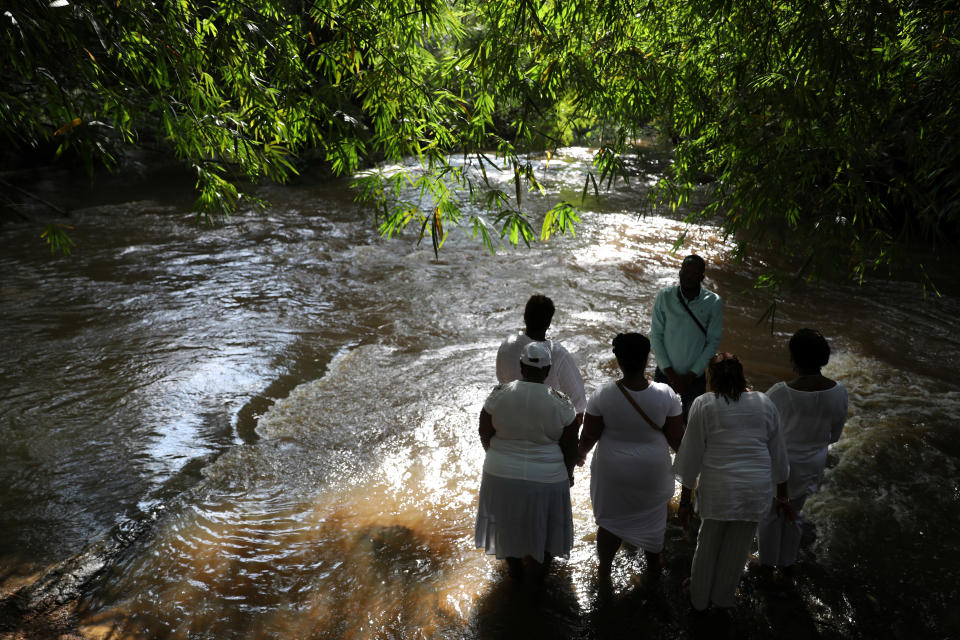 Tourists gather at the Assin Manso river, Ghana. Today the Assin Manso site is a sacred place of remembrance, and an image of slaves chained by the feet promises "Never again." (Photo: Siphiwe Sibeko/Reuters)