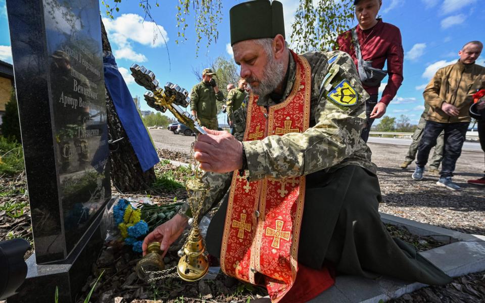 Military chaplain Yuriy Potikun leads a memorial service at the site of the death of three Ukrainian servicemen of the 113th Territorial Defence Brigade in 2022, at the northern outskirts of Kharkiv on April 24, 2023 - SERGEY BOBOK/AFP