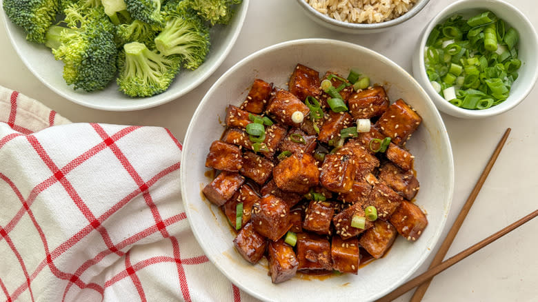 sriracha tofu in white bowl next to vegetables