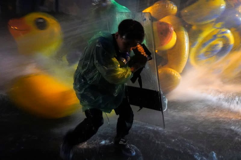 A demonstrator uses a shield as a protection against water cannons during an anti-government protest in Bangkok