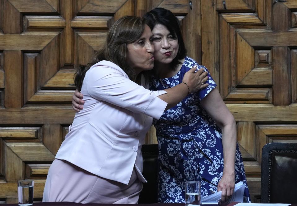 Peru's President Dina Boluarte, left, and Foreign Minister Ana Cecilia Gervasi embrace during a ceremony at the Foreign Ministry in Lima, Peru, Tuesday, Dec. 20, 2022. Peru's Congress is slated to consider a proposal on Tuesday to push up elections that have been a major demand of protesters blocking highways and clashing with security forces in deadly demonstrations across the country over the ouster of President Pedro Castillo. (AP Photo/Martin Mejia)