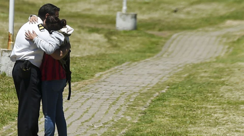 Relatives embrace outside the naval base. Source: Getty