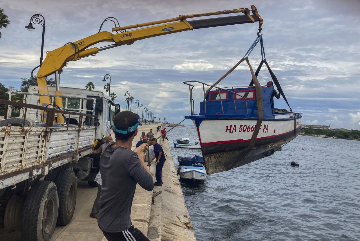 Workers remove a boat from the water in the bay of Havana, Cuba, Monday, Sept. 26, 2022.