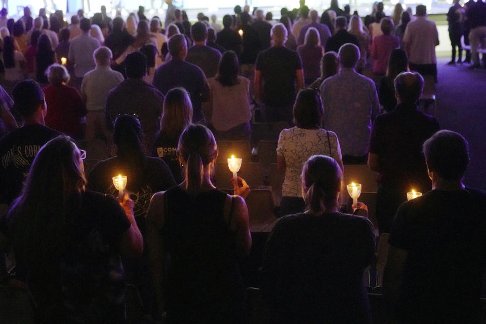 People hold candles as they join in a prayer vigil Friday, Aug. 25, 2023, at Saddleback Church in Lake Forest, Calif., for the victims of Wednesday's shootings at Cook's Corner in Trabuco Canyon, Calif. (AP Photo/Damian Dovarganes)