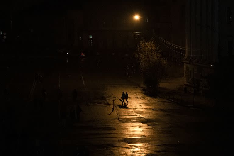 Gente cruzando una calle durante un apagón en Kiev, Ucrania, el domingo 6 de noviembre de 2022. (AP Foto/Andrew Kravchenko)