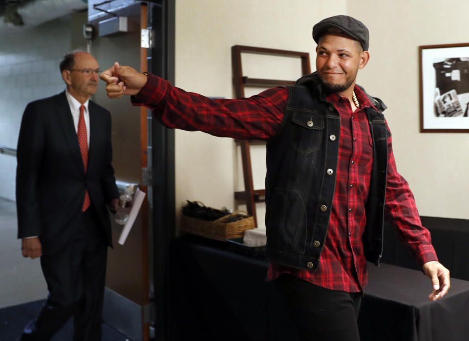 St. Louis Cardinals catcher Yadier Molina, right, waves to family members while followed by Cardinals' Bill DeWitt Jr., left, as they enter a news conference ahead of a baseball game against the Chicago Cubs, Sunday, April 2, 2017, in St. Louis. The Cardinals have finalized a contract extension with seven-time All-Star Molina that runs through the 2020 season. (AP Photo/Jeff Roberson)