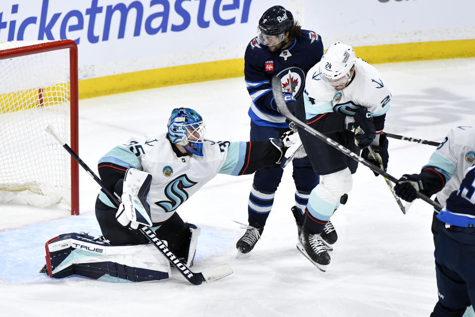 Seattle Kraken's Jamie Oleksiak (24) blocks a shot as he defends against Winnipeg Jets' Alex Iafallo (9) in front of goaltender Joey Daccord (35) during the third period of an NHL hockey game Tuesday, March 5, 2024, in Winnipeg, Manitoba. (Fred Greenslade/The Canadian Press via AP)
