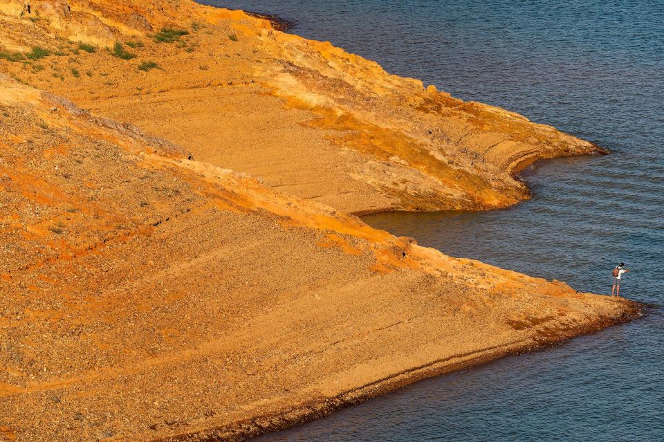 man fishes on dry orange banks of shasta lake