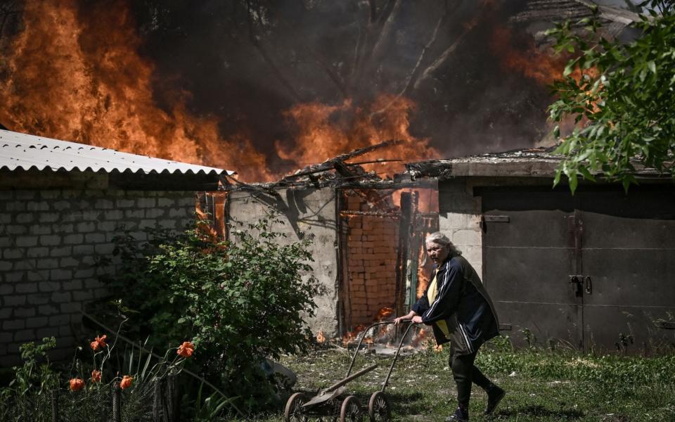 An elderly woman walks away from a burning house garage after shelling in the city of Lysytsansk at the eastern Ukrainian region of Donbas on May 30, 2022, on the 96th day of the Russian invasion of Ukraine. - Since failing to capture Kyiv in the war's early stages, Russia's army has narrowed its focus, hammering Donbas cities with artillery and missile barrages as it seeks to consolidate its control. (Photo by ARIS MESSINIS / AFP) (Photo by ARIS MESSINIS/AFP via Getty Images) ***BESTPIX***  - ARIS MESSINIS/AFP via Getty Images