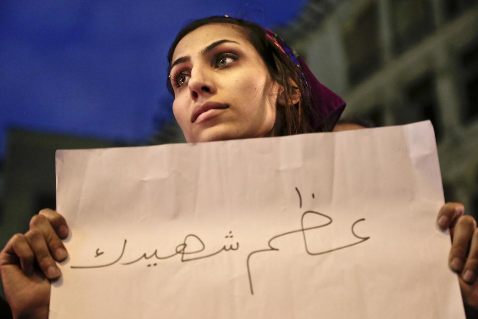 A woman holds a paper with Arabic that reads, "hold your martyr high," during a vigil for victims of a Sunday bombing at a Coptic cathedral, in downtown Cairo, Egypt, Wednesday, Dec. 14, 2016. Twenty five Christians were killed at the city's main Coptic cathedral in what was one of the deadliest attacks on the religious minority in recent memory. The bomb went off while worshippers were attending Sunday Mass at a chapel adjacent to St. Mark's Cathedral. (AP Photo/Nariman El-Mofty)