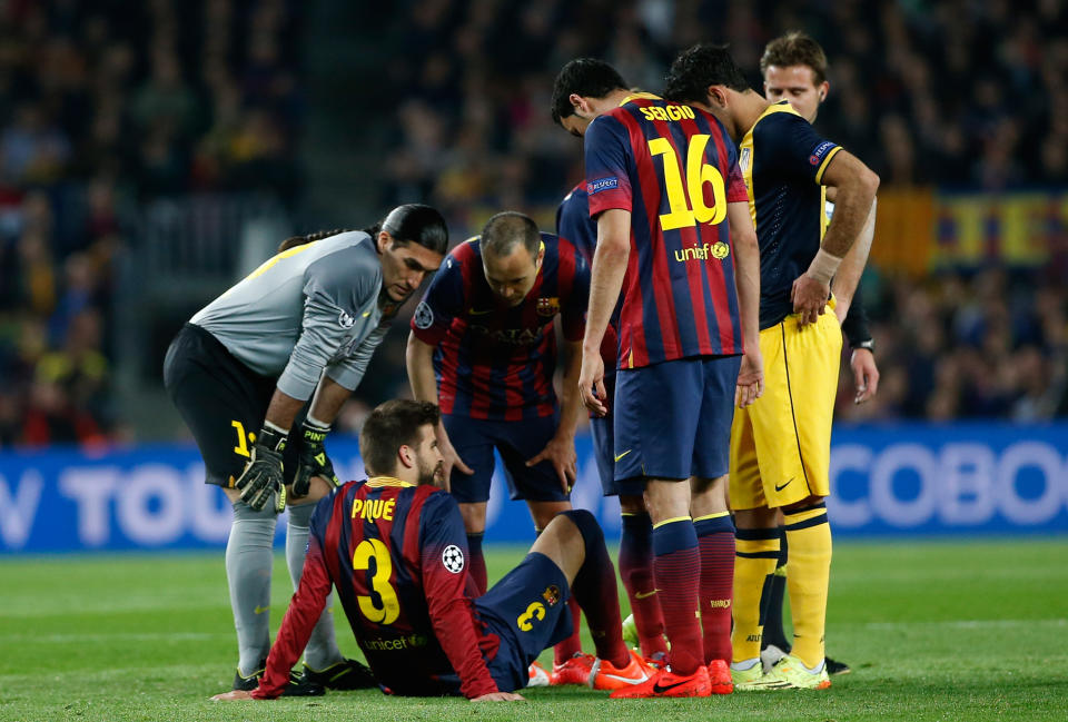 Players check on Barcelona's Gerard Pique, on the ground, after he injured himself during a first leg quarterfinal Champions League soccer match between Barcelona and Atletico Madrid at the Camp Nou stadium in Barcelona, Spain, Tuesday April 1, 2014. Pique had to be substituted. (AP Photo/Emilio Morenatti)