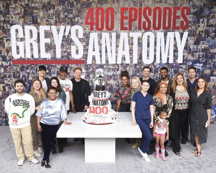 The cast of "Grey's Anatomy" surround a multi-tiered cake celebrating 400 episodes