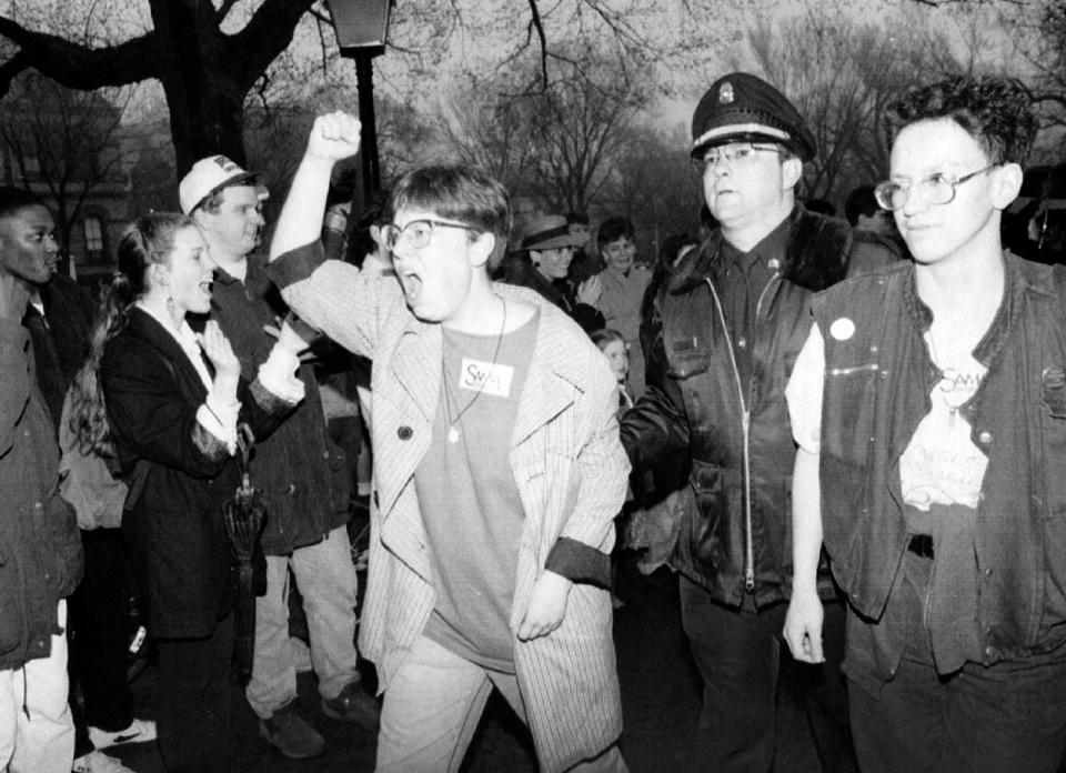 April 22, 1992: Two Brown University students cheer to a crowd as they are led from the president's office. About 200 students were arrested for staging a daylong sit-in over financial aid practices.