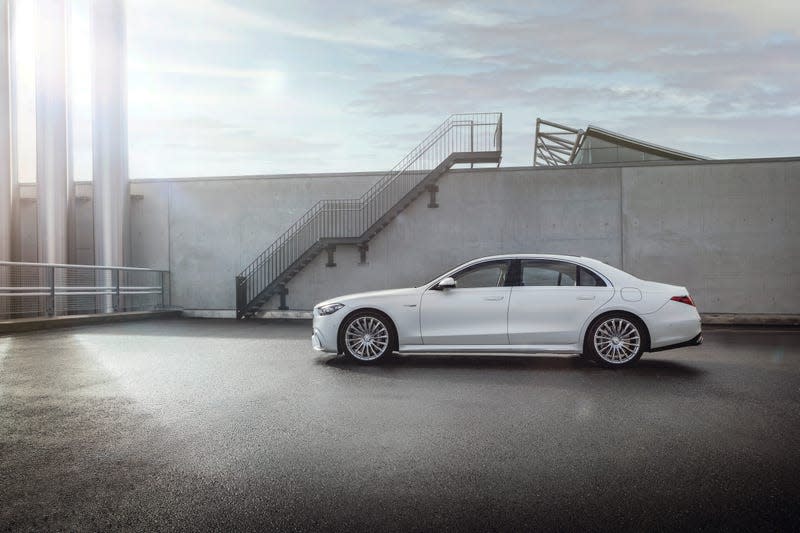 a white 2023 mercedes-amg s 63 e performance sedan seen from the drivers side in silhouette, parked on the roof of a concrete parking structure against a gray wall