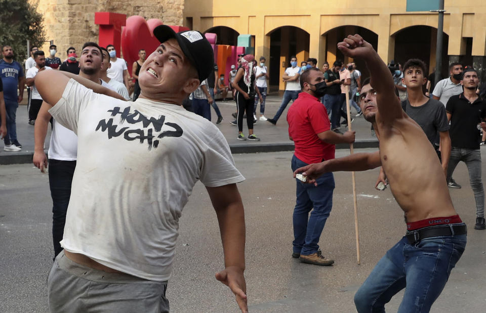 Anti-government protesterS throw stones towards police near Parliament Square, In Beirut, Lebanon, Tuesday, Sept. 1, 2020. On a visit to Lebanon, French President Emmanuel Macron issued a stern warning to Lebanon's political class Tuesday, urging them to commit to serious reforms within a few months or risk punitive action, including sanctions, if they fail to deliver. (AP Photo/Bilal Hussein)