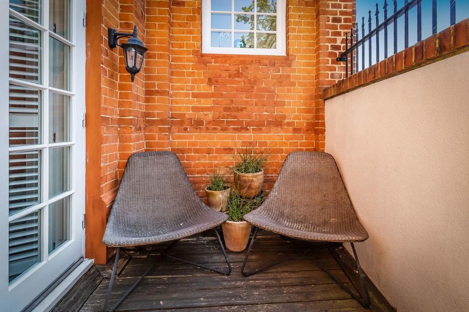 a small courtyard terrace with two brown chairs