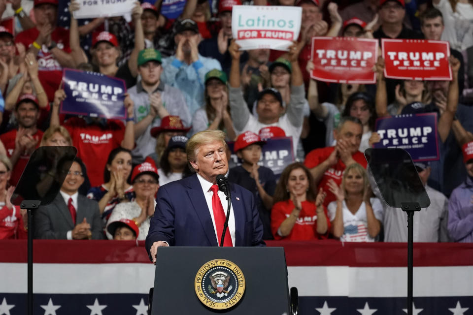 Jorge Rivas sostiene un cartel de Latinos por Trump en un mitin de campaña del presidente en Phoenix. (AP Photo/Rick Scuteri)