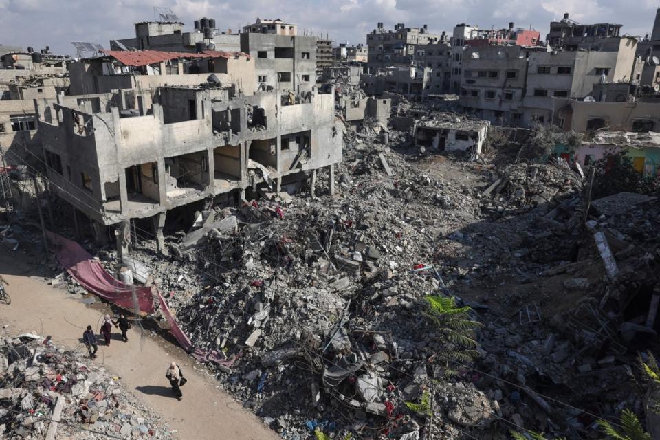 People walk past buildings destroyed following the Israeli bombardment of Bureij in the centre of Gaza Strip (AFP/Getty)